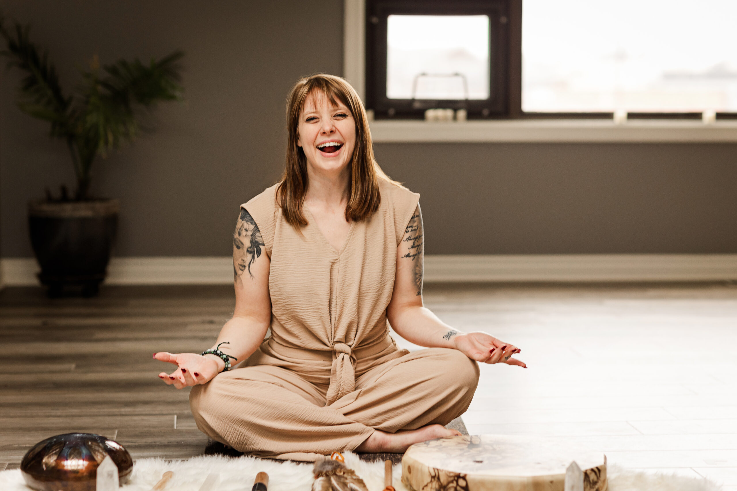 A woman laughing during her meditation in a yoga studio with windows.